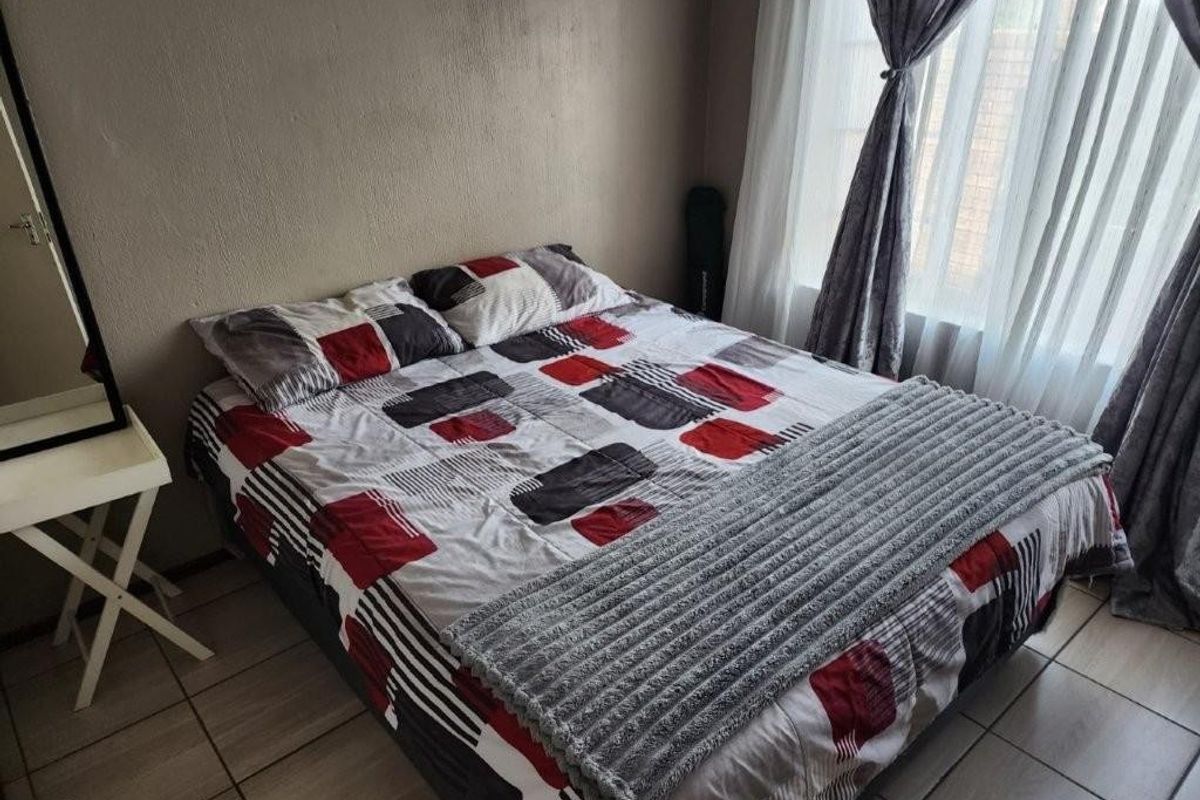 A bedroom featuring tiled flooring and a window with curtain treatments.