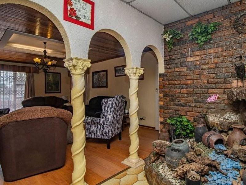 Living area featuring decorative arched columns, exposed brick feature wall with integrated indoor water feature, and wood-paneled ceiling details.