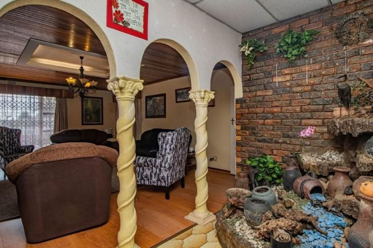Living area featuring decorative arched columns, exposed brick feature wall with integrated indoor water feature, and wood-paneled ceiling details.