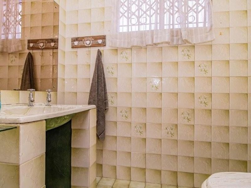 A dated bathroom featuring original wall tiles, a built-in tiled vanity with a basin, and a standard toilet.