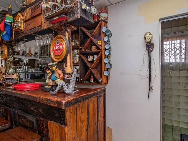 A rustic built-in wooden bar area featuring integrated shelving and cabinetry, adjacent to a tiled bathroom space.