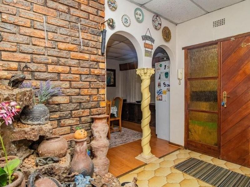 Entrance hall featuring a rustic brick feature wall, decorative archways, and a solid timber front door with textured glass panels.