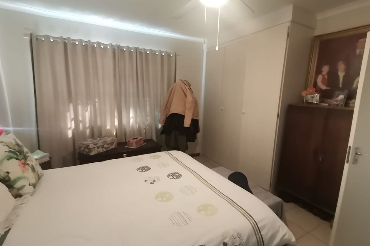 A bedroom featuring built-in cupboards, a ceiling fan, and tiled flooring, providing a functional and comfortable living space.