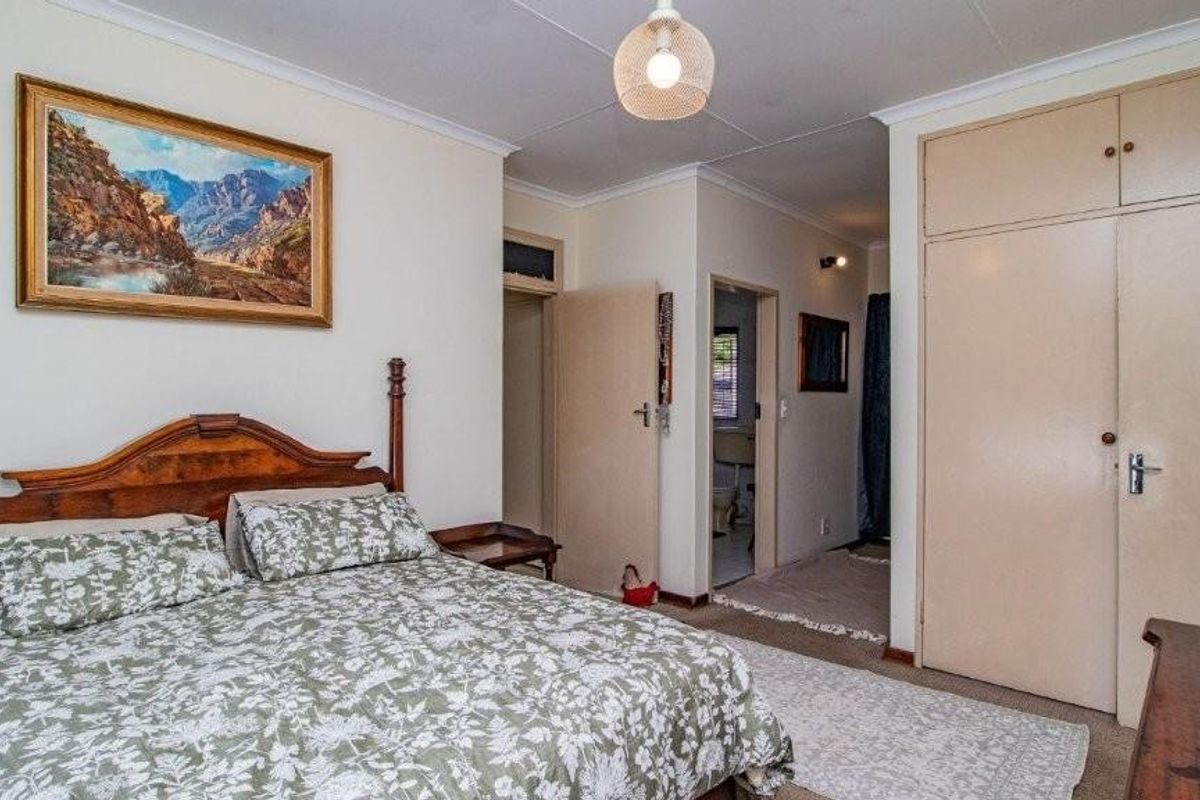 A bedroom featuring built-in cupboards and direct access to an en-suite bathroom, finished with neutral walls and carpeted flooring.