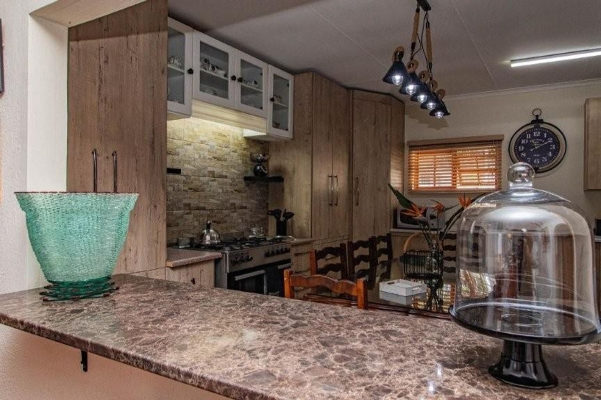 A well-appointed kitchen featuring wood-look cabinetry, stone-style backsplash, built-in gas stove, and a breakfast bar counter.