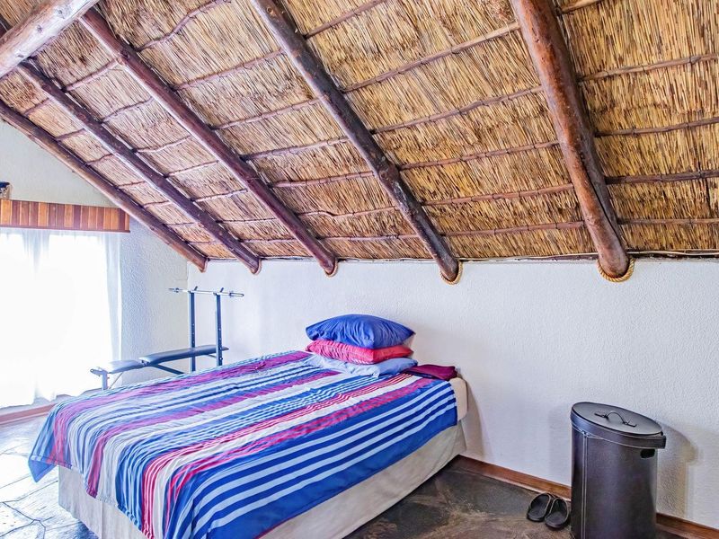 A bedroom featuring a distinctive vaulted thatched roof with exposed timber beams and stone flooring.