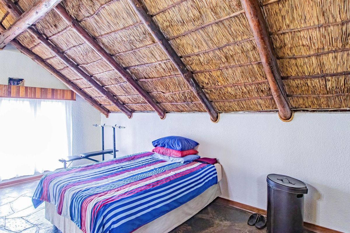 A bedroom featuring a distinctive vaulted thatched roof with exposed timber beams and stone flooring.