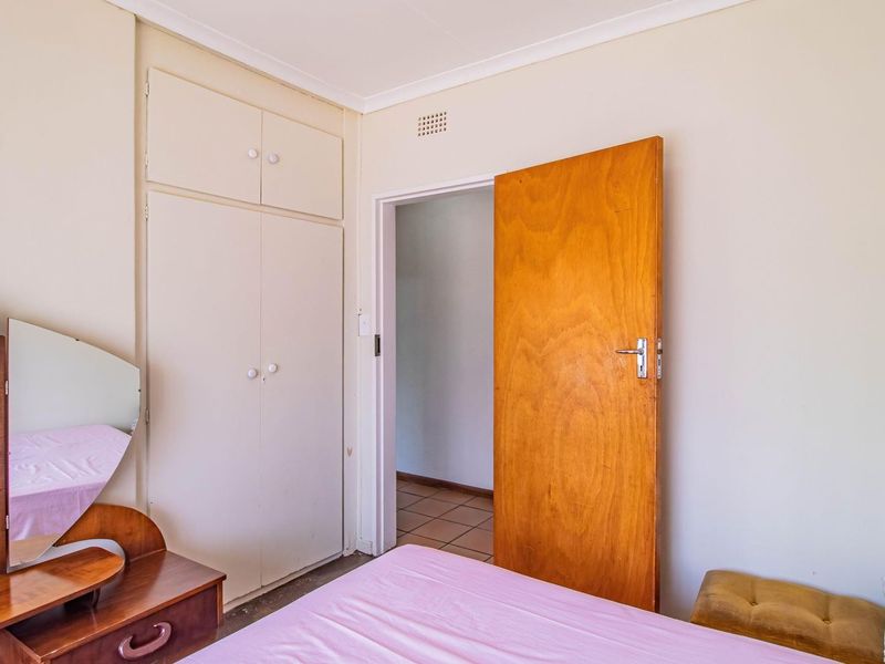 A bedroom featuring built-in cupboards and a wooden door, providing functional storage and access to the adjacent hallway.