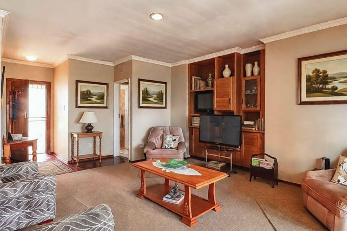 A comfortable living room featuring built-in wooden cabinetry, recessed ceiling lighting, and crown molding, providing a functional and traditional living space.