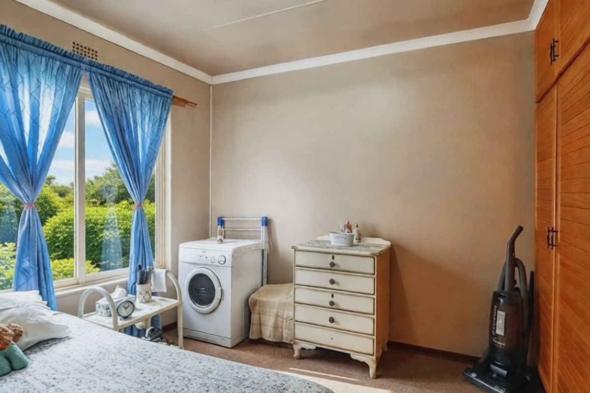 A bedroom featuring built-in wooden cabinetry and a large window with garden views, currently utilized with a laundry appliance.