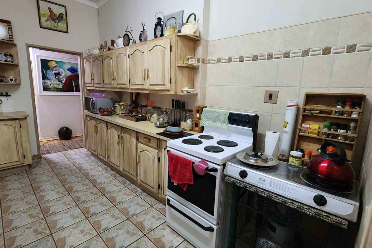 A functional kitchen featuring traditional wooden cabinetry, tiled backsplash, and a freestanding stove, offering a classic layout with ample storage space.