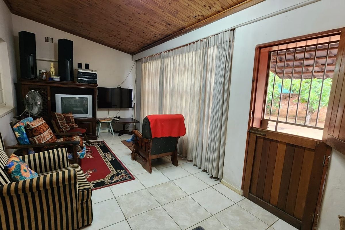 A living room featuring tiled flooring, a timber-paneled vaulted ceiling, and a stable-style wooden door leading to the exterior.