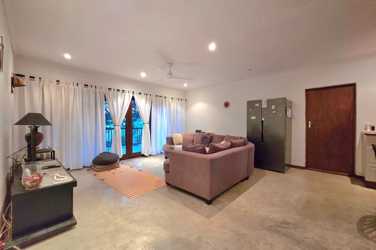 Spacious living area featuring polished concrete floors, recessed downlighting, a ceiling fan, and direct access to an outdoor balcony through glass doors.
