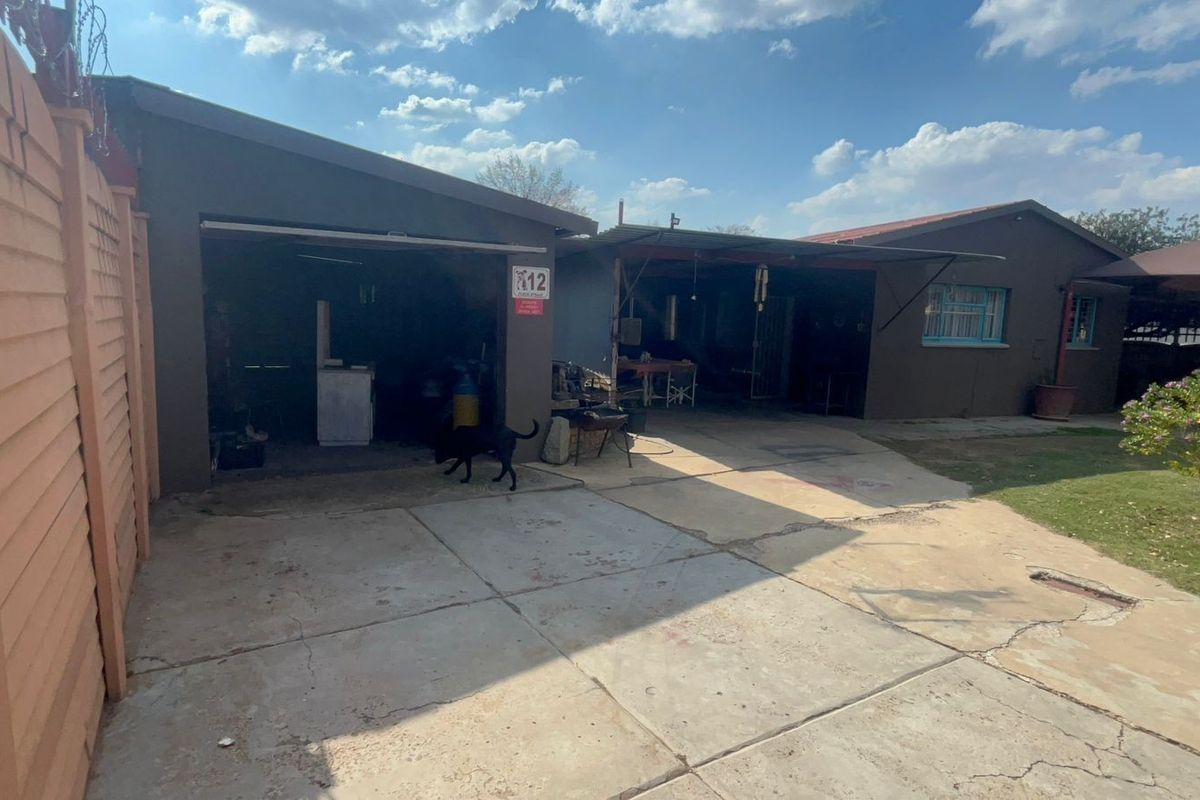 Exterior view of the property featuring a concrete driveway, garage access, and a covered outdoor area with a garden space.