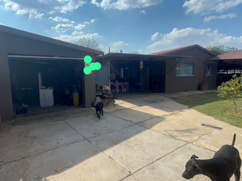 Rear exterior view of the property featuring a concrete driveway, a garage, and a covered patio area with a small lawn.