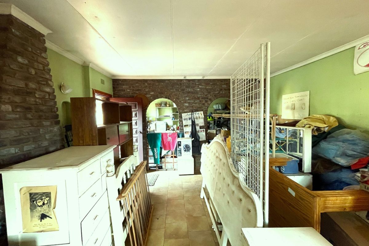 A living area featuring exposed brick walls, tiled flooring, and arched doorways leading to an adjacent space.