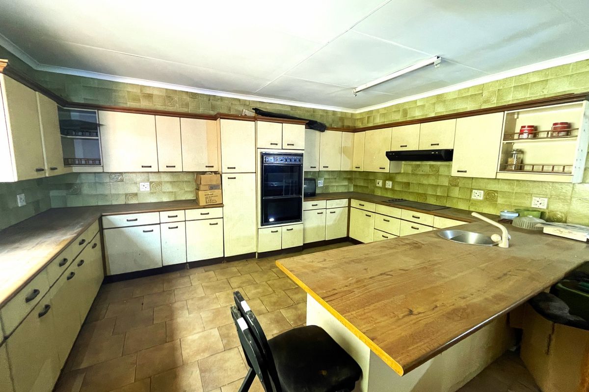 Spacious kitchen featuring extensive cabinetry, built-in double oven, integrated cooktop, and a large central island with a sink.