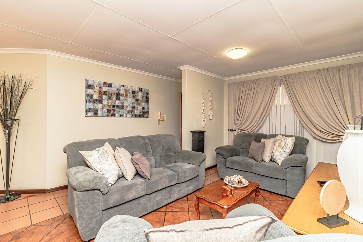 A comfortable living room featuring terracotta floor tiles, neutral walls, and a drop-in ceiling, providing a functional and traditional living space.