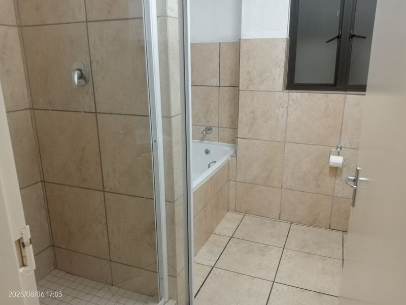 A functional bathroom featuring a separate shower enclosure, a built-in bathtub, and neutral ceramic tiling throughout.