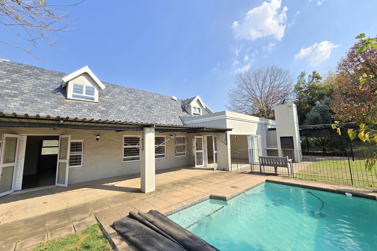 Rear view of the property featuring a swimming pool, paved patio area, and a covered outdoor space with a built-in fireplace.