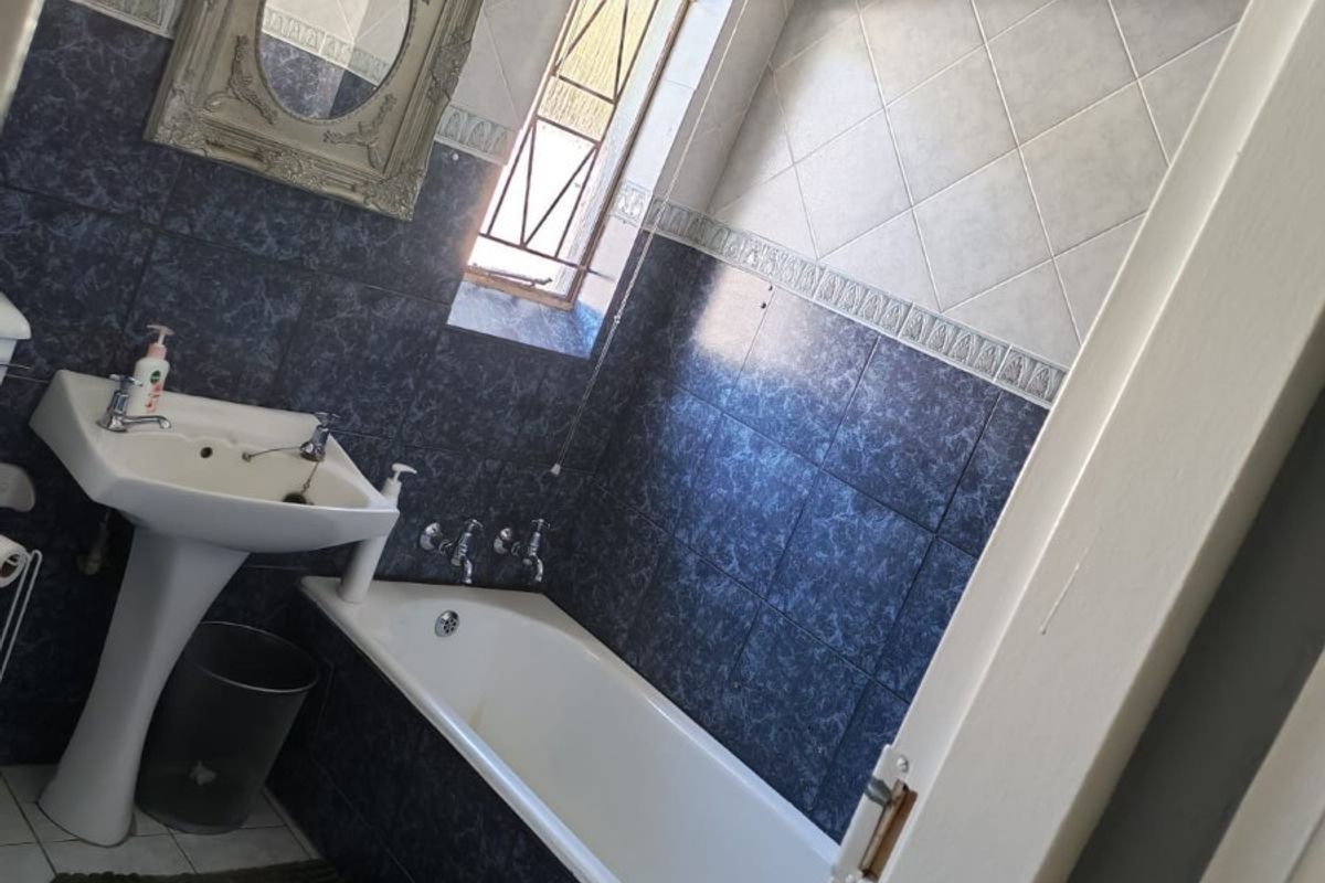 A functional bathroom featuring a pedestal basin, a built-in bathtub, and decorative wall tiling.