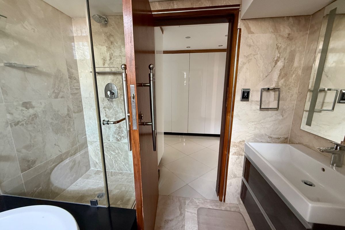 Modern bathroom featuring marble-style wall and floor tiling, a glass-enclosed shower, and a contemporary vanity unit with a basin.