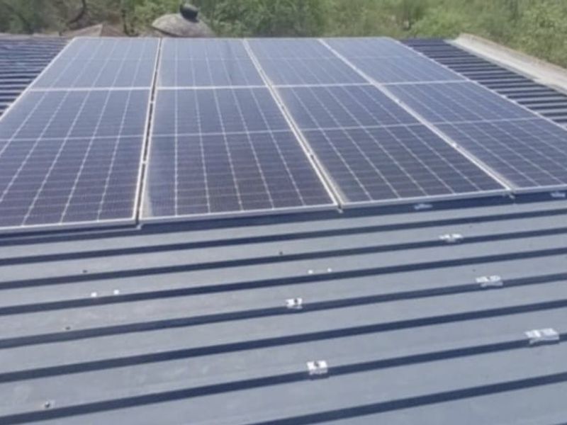A view of a corrugated metal roof featuring a mounted solar panel array for energy efficiency.