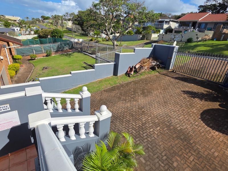 Elevated view of the paved driveway, garden area, and boundary walls surrounding the property.