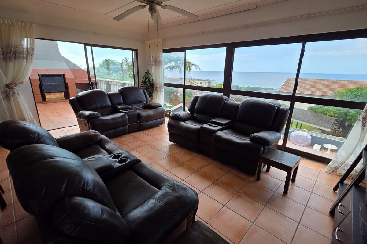 Spacious living area featuring large sliding glass doors that open to a patio, offering expansive ocean views and abundant natural light.