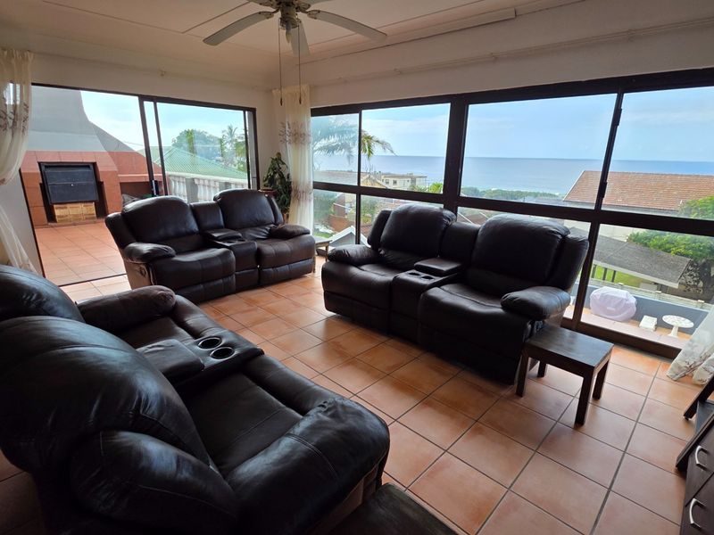 Spacious living area featuring large sliding glass doors that open to a patio, offering expansive ocean views and abundant natural light.