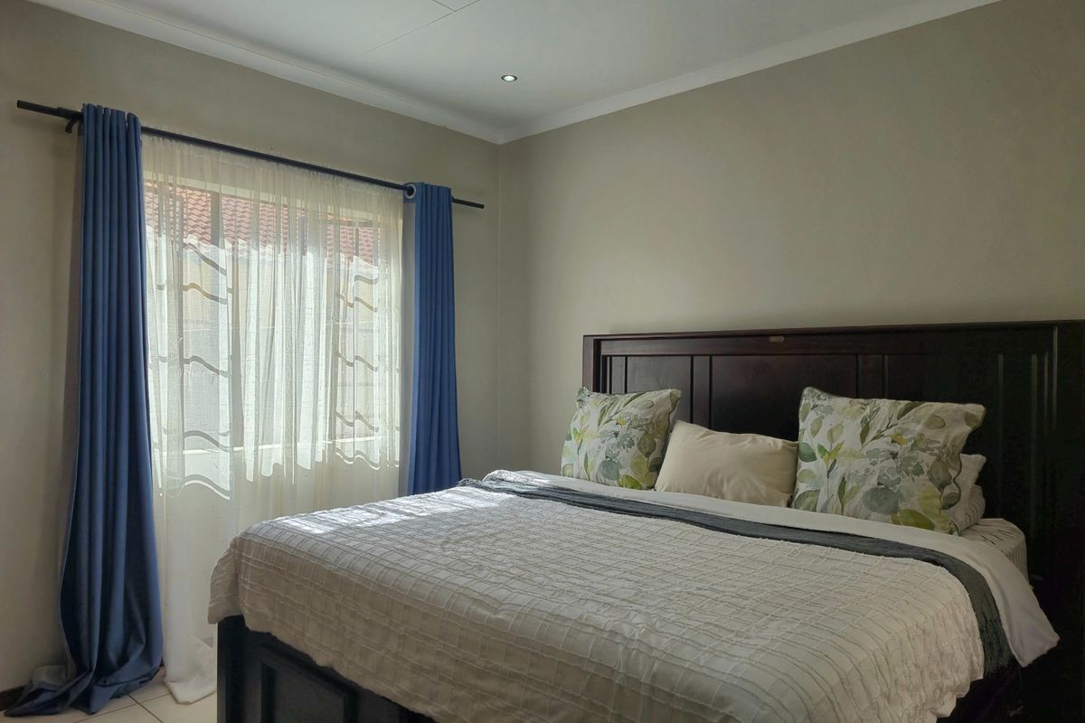 A well-maintained bedroom featuring neutral wall tones, tiled flooring, and recessed downlighting, providing a comfortable and functional living space.