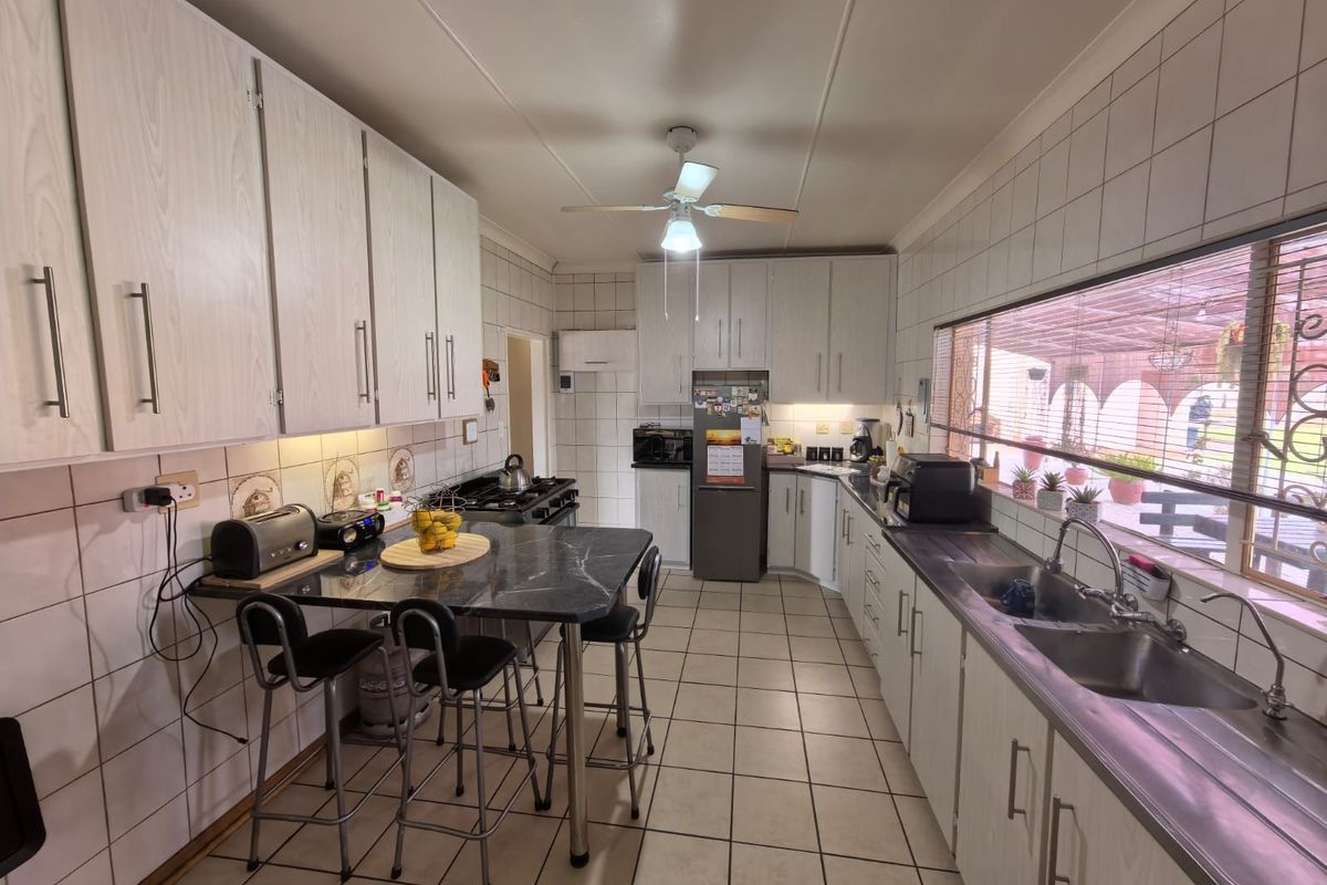 A functional kitchen featuring white cabinetry, tiled walls, a double stainless steel sink, and a built-in breakfast bar area.