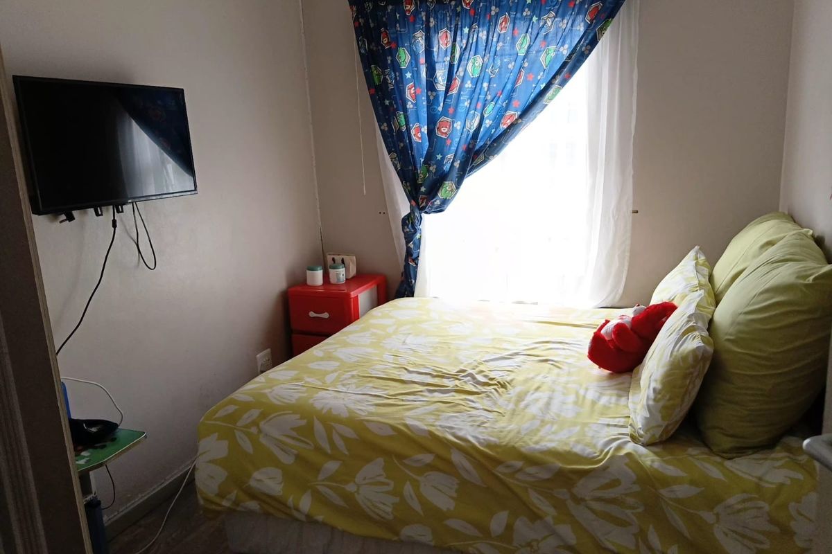 A compact bedroom featuring a window with curtains and wall-mounted television bracket.
