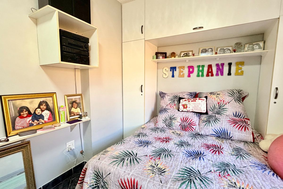 A compact bedroom featuring built-in white cabinetry and overhead storage units, providing efficient space utilization.