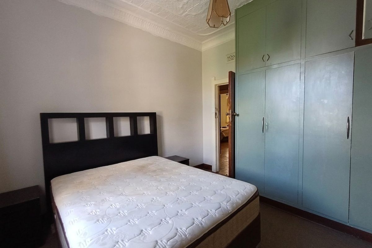 A bedroom featuring built-in cupboards, decorative ceiling molding, and a central light fixture.