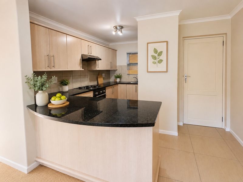 A well-maintained kitchen featuring light wood cabinetry, dark granite countertops, built-in oven and hob, and neutral tiled flooring.