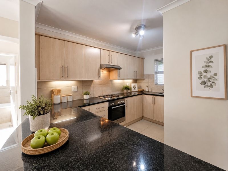 A well-maintained kitchen featuring light wood cabinetry, dark granite countertops, a built-in oven, gas hob, and integrated under-cabinet lighting.