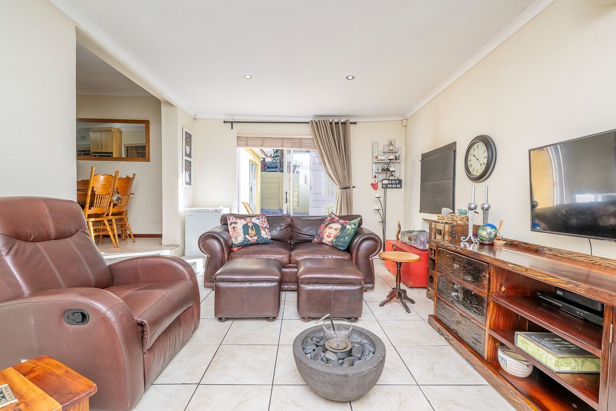 A comfortable living room featuring tiled flooring and recessed lighting, with an open-plan layout connecting to the adjacent dining area and kitchen.