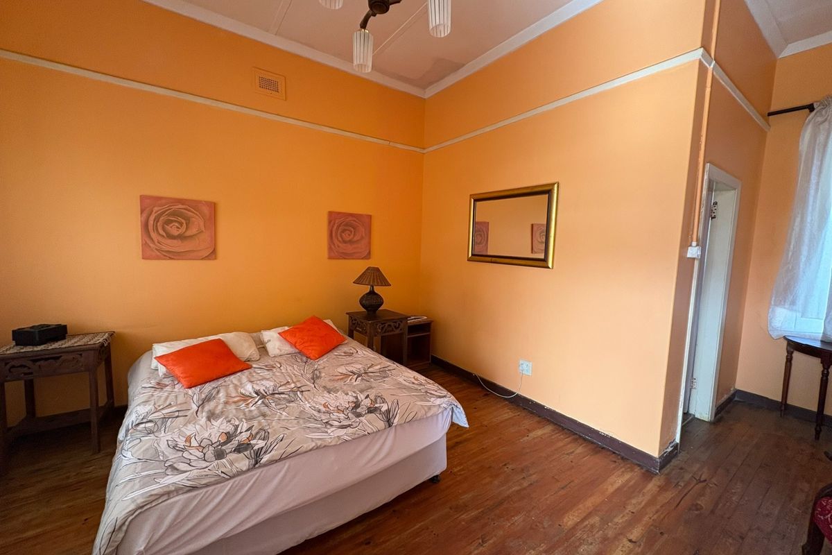 A bedroom featuring original wooden flooring, high ceilings with crown molding, and a neutral layout ready for personalization.