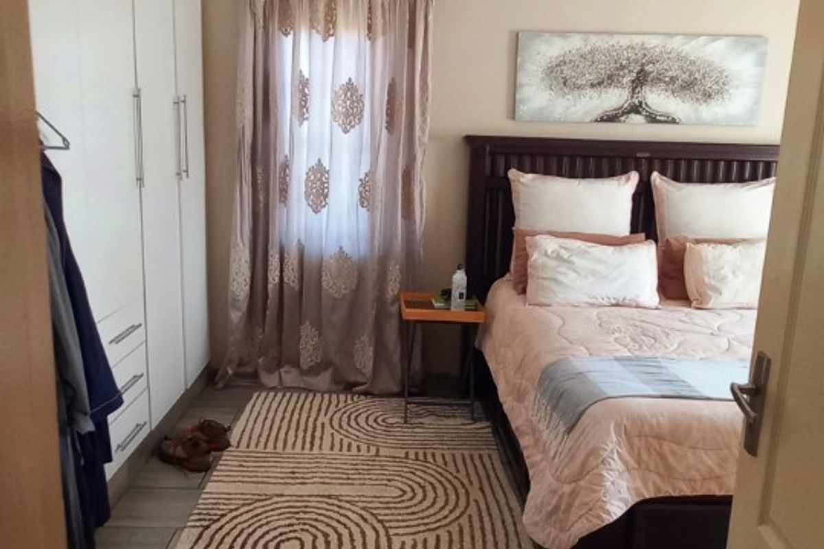 A well-maintained bedroom featuring built-in floor-to-ceiling wardrobes, tiled flooring, and recessed ceiling lighting.