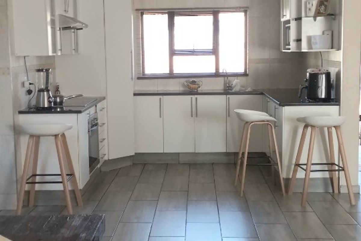 A functional kitchen featuring white cabinetry, dark countertops, tiled flooring, and a window providing natural light.