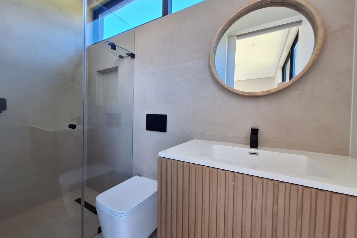 Modern bathroom featuring a floating vanity with a stone countertop, wall-mounted toilet, and a glass-enclosed walk-in shower with a recessed niche.