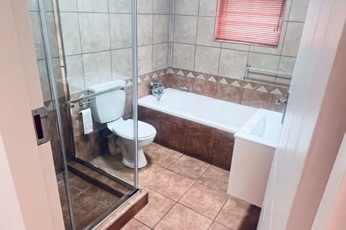 A functional bathroom featuring a glass-enclosed shower, a built-in bathtub, and tiled finishes throughout.