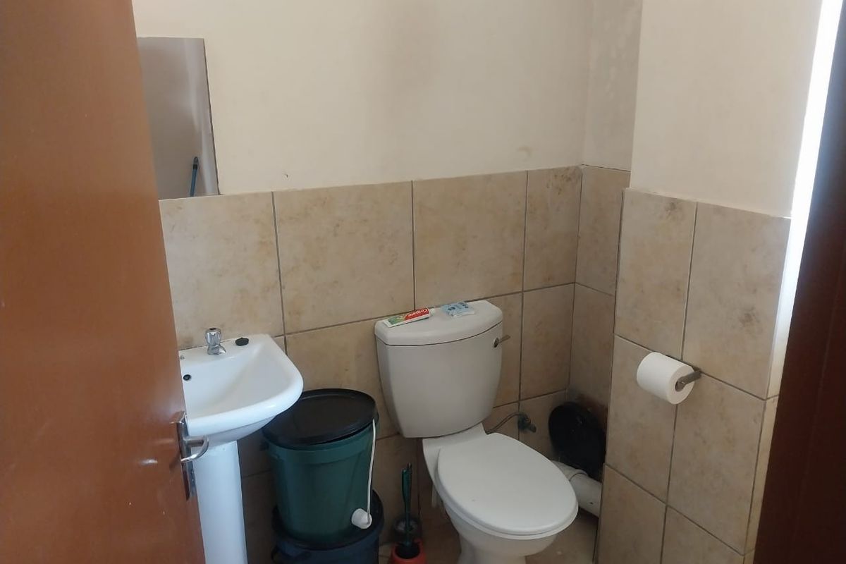 A functional bathroom featuring a pedestal basin, a standard toilet, and neutral wall tiling.