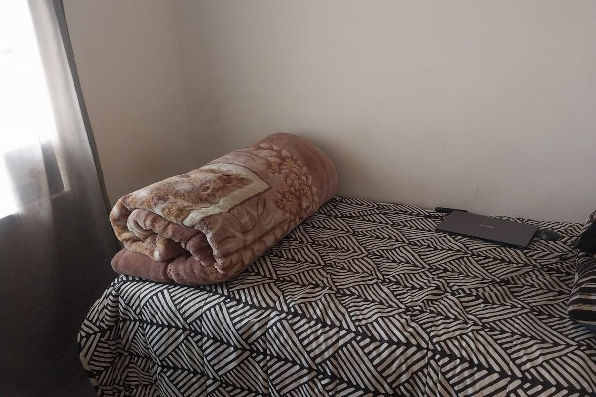 A bedroom featuring a window with curtains, providing natural light and a simple, functional layout.