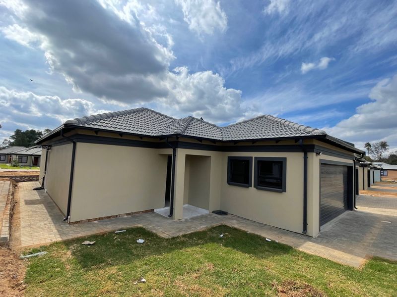 Modern single-story residential home featuring a tiled roof, neutral exterior paint, dark window frames, and an integrated garage with paved driveway access.
