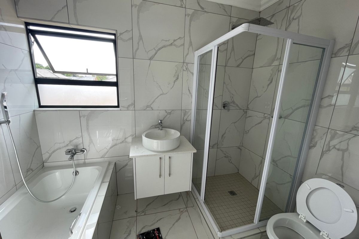 Modern bathroom featuring marble-look wall and floor tiles, a built-in bathtub, a separate shower enclosure, and a wall-mounted vanity with a vessel sink.