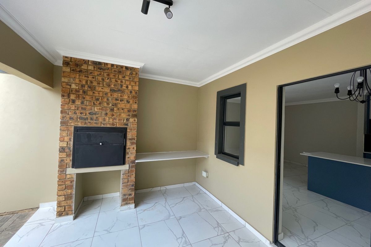 Covered patio area featuring a built-in brick braai, modern marble-look tiled flooring, and direct access to the interior living space.