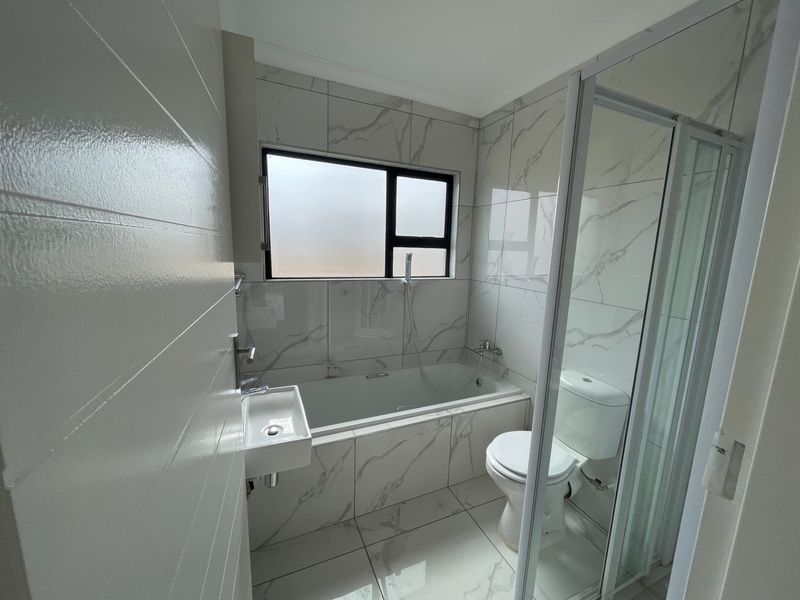 Modern bathroom featuring marble-look porcelain tiling, a built-in bathtub, a separate shower enclosure, and a wall-mounted basin.