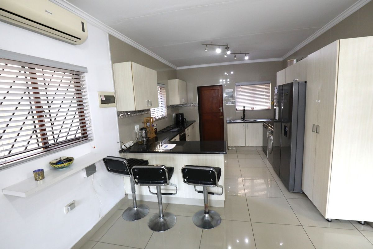 A functional kitchen featuring a breakfast bar, built-in cabinetry, tiled flooring, and integrated appliance space, offering a practical layout for daily living.